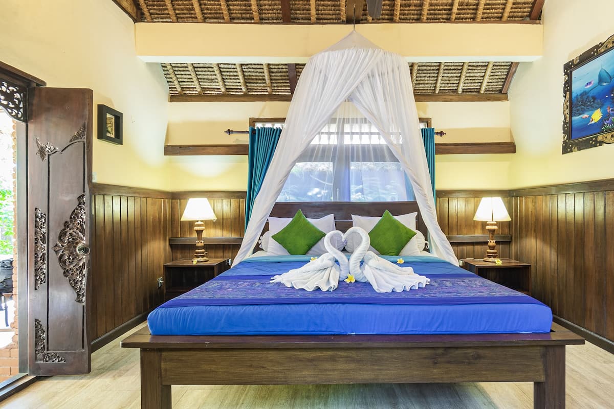 A room with a bed, two nightstands, a canopy bed, a wall painting, and a wooden ceiling.