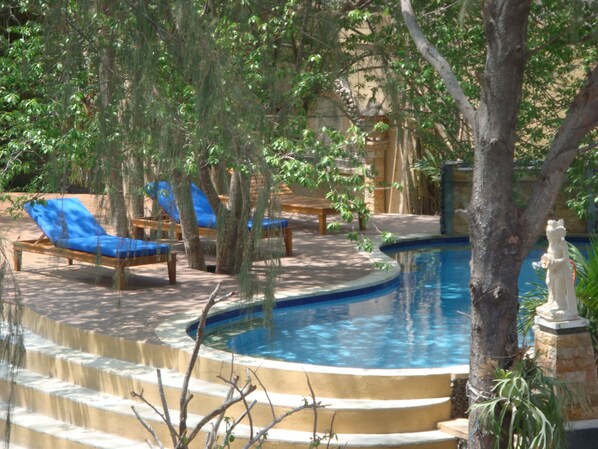 Un área de piscina con sillones de descanso y una estatua.