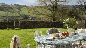 An outdoor dining table with a view of rolling hills and a stone wall. - The Manger, Perched in an elevated position within the Blackdown Hills National Landscape. (Axminster)