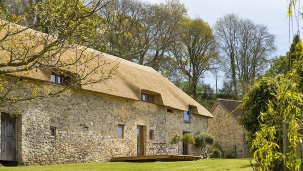 A stone building with a thatched roof, a wooden door, and a small window. - The Manger, Perched in an elevated position within the Blackdown Hills National Landscape. (Axminster)