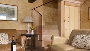 A living room with a sofa, a coffee table with a wine bottle and glass, a lamp, and a staircase. - The Manger, Perched in an elevated position within the Blackdown Hills National Landscape. (Axminster)