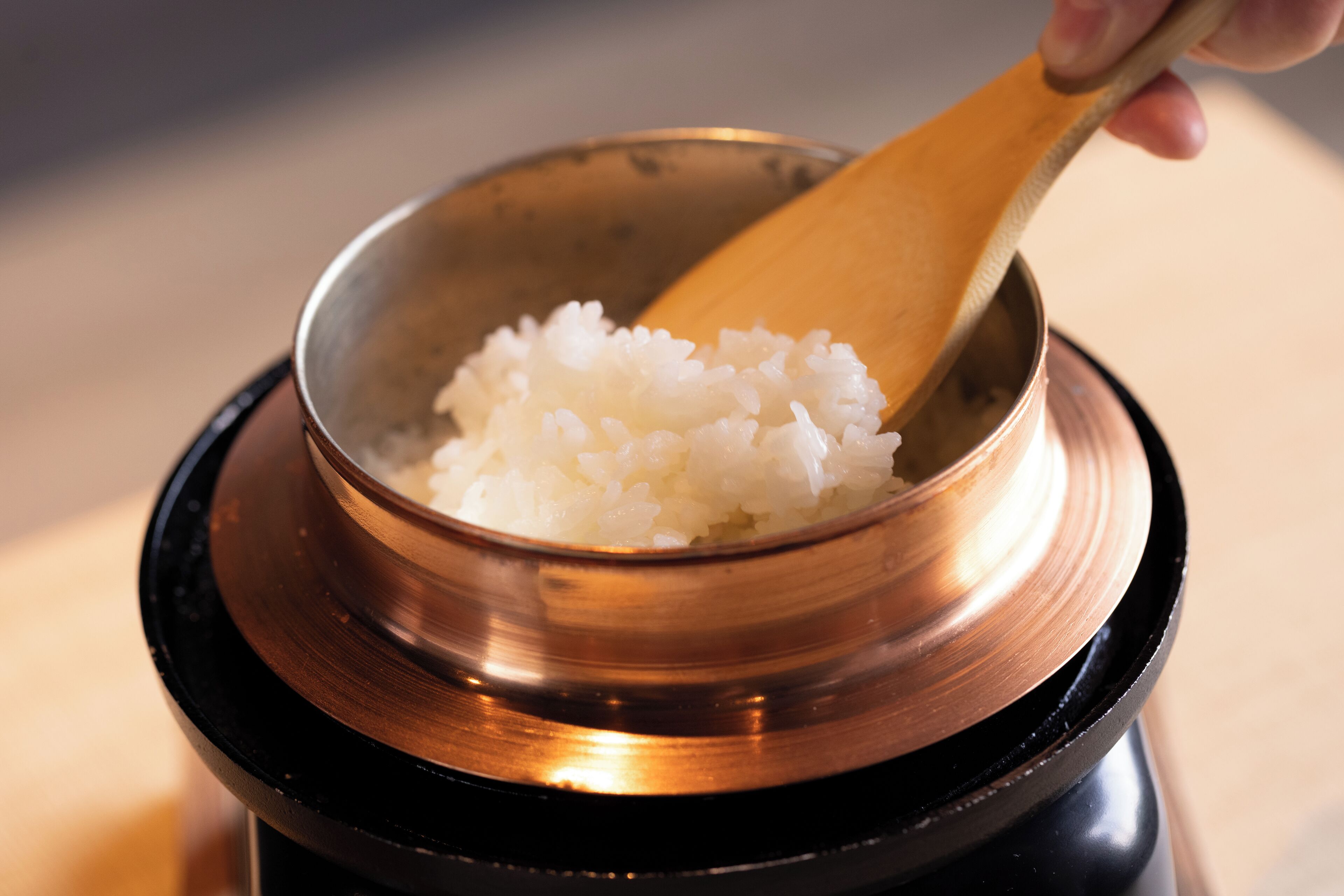 A bowl of white rice on a black and copper base.