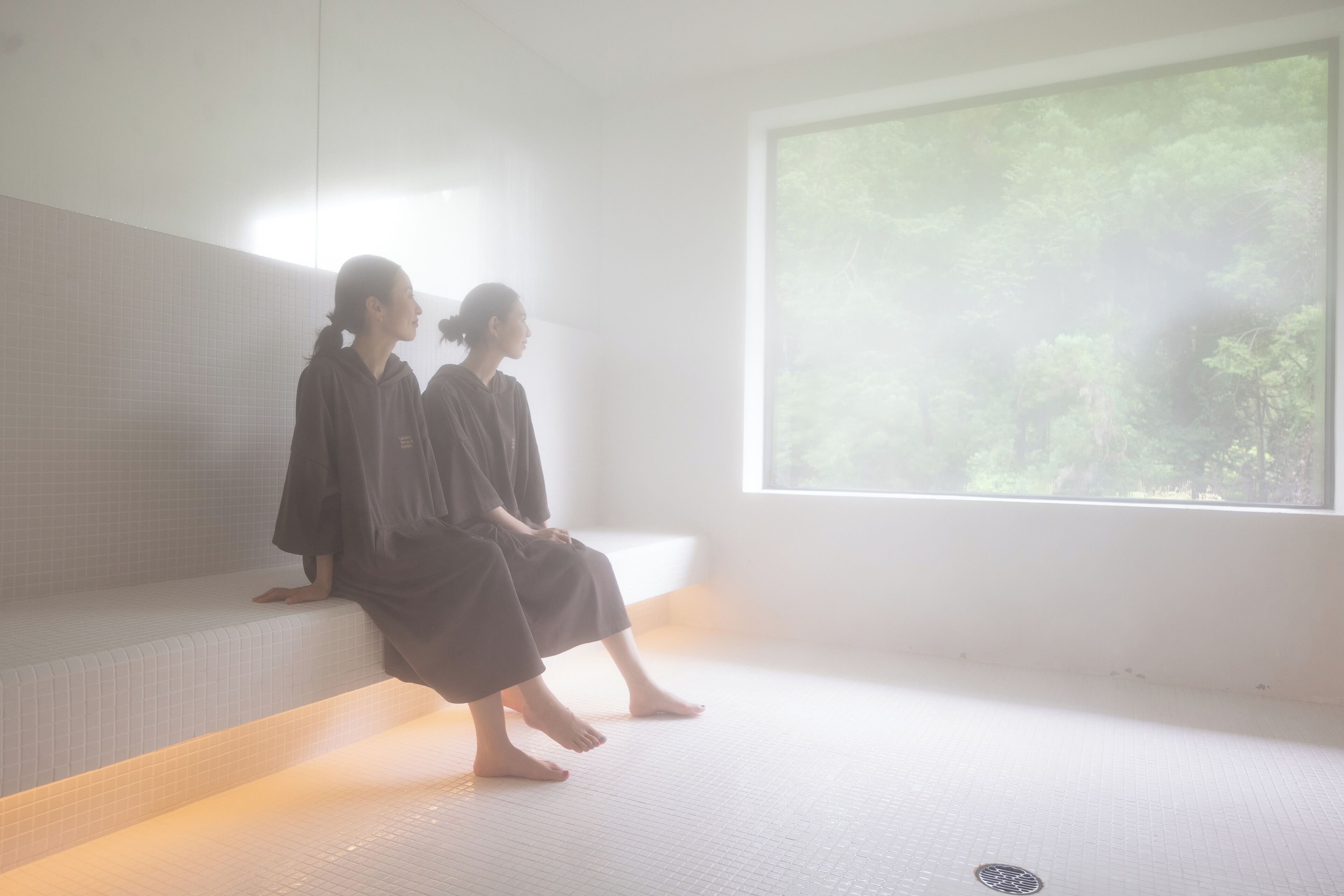 A room with a large window, a bench, and a tiled floor.