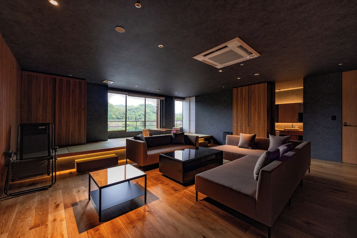 A modern living room with a sofa, armchairs, a coffee table, and a TV.