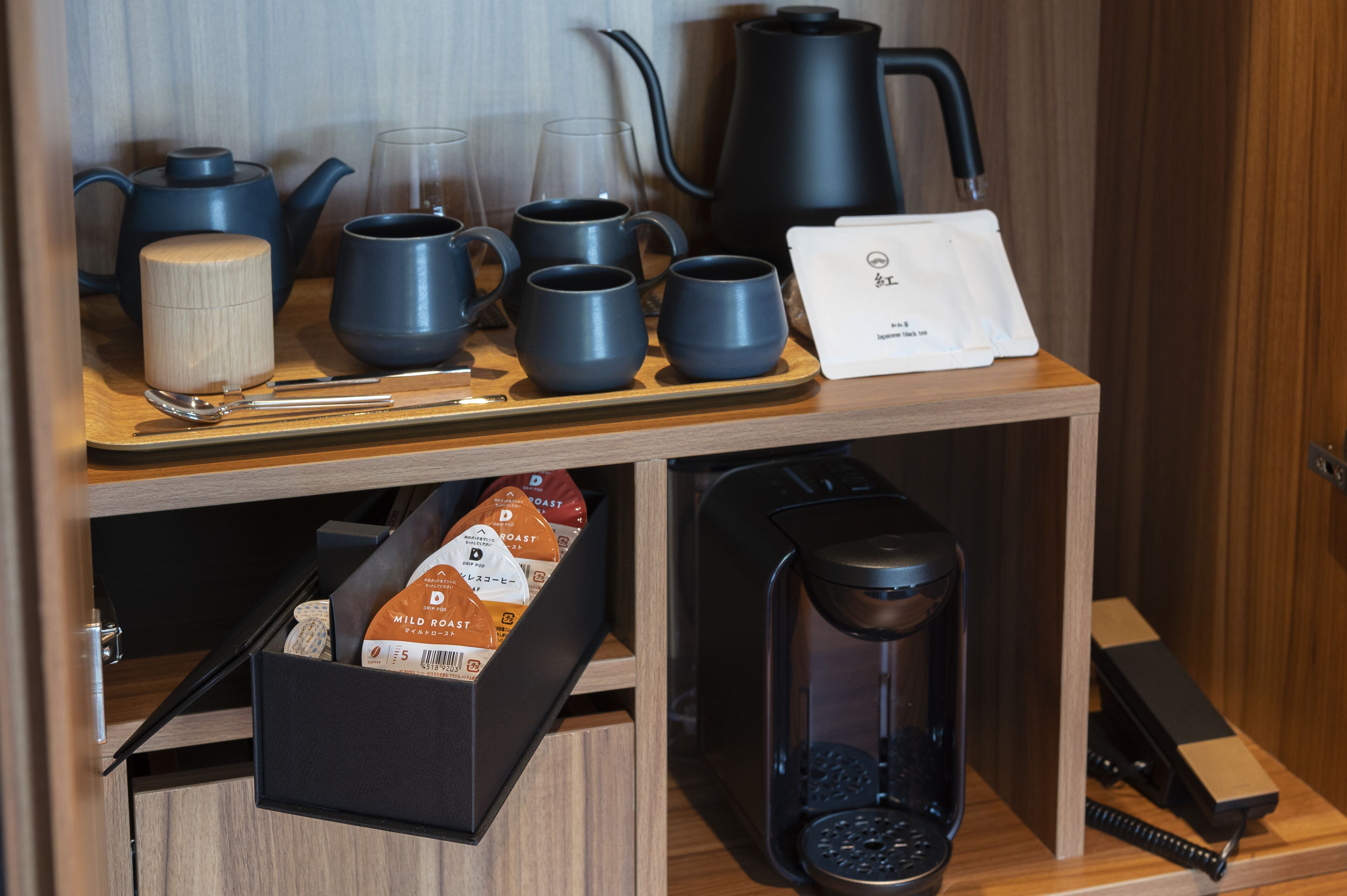 Una mesa de madera con diversos utensilios para té y café, incluyendo un hervidor, tazas y una cafetera.