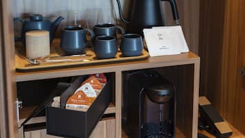 Una mesa de madera con diversos utensilios para té y café, incluyendo un hervidor, tazas y una cafetera.