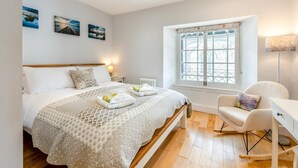 Een slaapkamer met een bed, een stoel, een raam en kunst aan de muur.