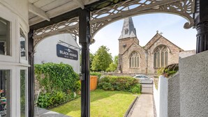 Een gebouw met een bordje voor 'Black Horse Real Ales' en een kerk met een toren op de achtergrond.