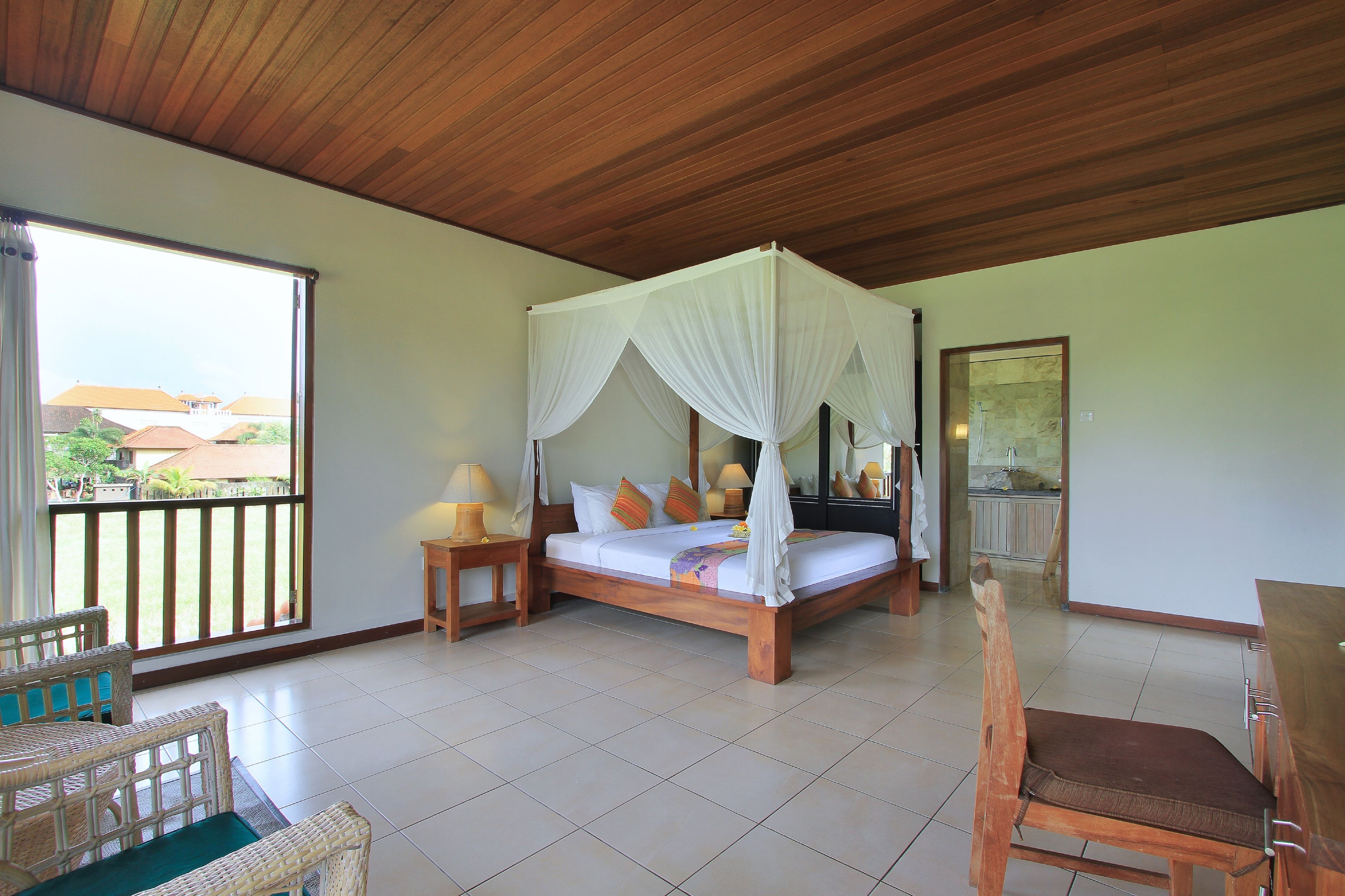 A bedroom with a four-poster bed, a wooden ceiling, and a view of the outside.