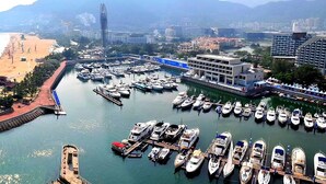A coastal marina with boats docked, a sandy beach, and a cityscape in the background. - Da Mei Sha Yacht Club Resort (Shenzhen)