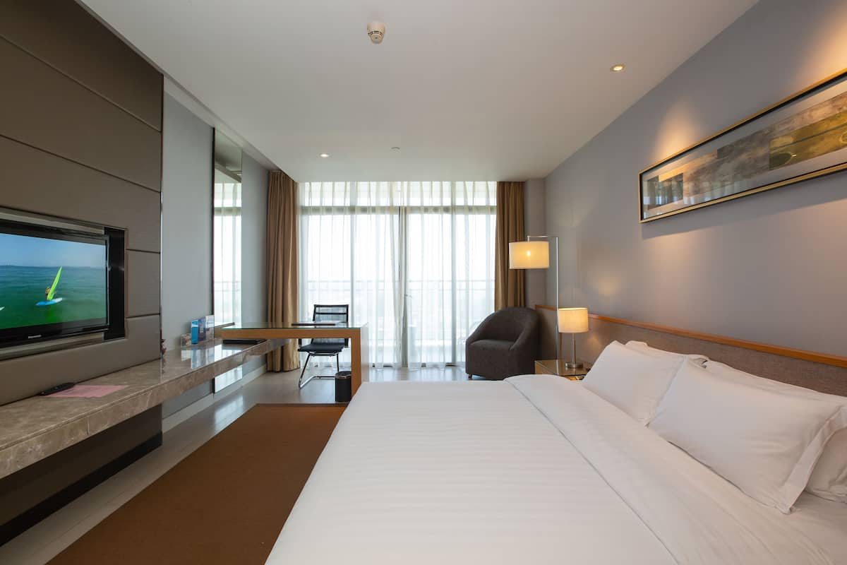 Una habitación de hotel con una cama grande, un escritorio con una silla, un televisor y un cuadro en la pared.