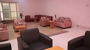 En rummelig lobby med flere siddeområder, herunder sofaer og stole, arrangeret omkring et centralt sofabord.