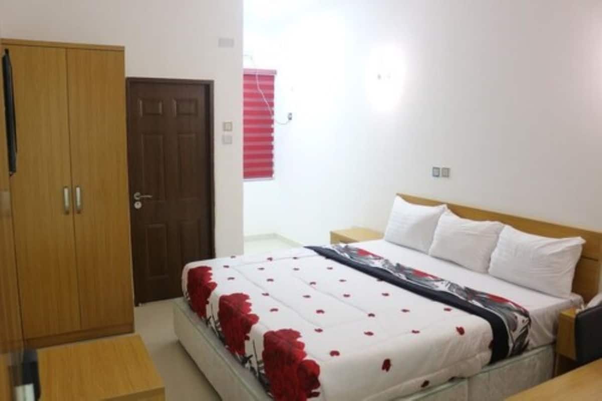 A bedroom with a bed, a wardrobe, and a window with blinds.