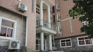 En bygning med flere etager, central balkon, aircondition og en facade i sten.