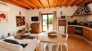 A room with a wooden ceiling, a dining table, a sofa, a TV, a kitchen area, and a balcony with a view. - Wonderful views of the sea and the volcanoes. Casa Isabel  (Tías)