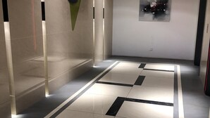 A modern hallway with a tiled floor, recessed lighting, and a wall-mounted artwork. - Elegant Cube Soho One South (Seri Kembangan)