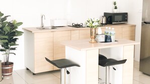 A modern kitchen with a sink, a microwave, a refrigerator, and a dining area with stools. - Elegant Cube Soho One South (Seri Kembangan)