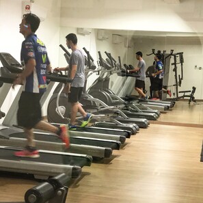 A gym with multiple treadmills in a row, a mirrored wall, and a wooden floor. - Elegant Cube Soho One South (Seri Kembangan)