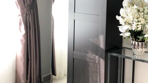 A room with a sliding door, a glass table with a vase of white flowers, and a view of a white building outside. - Elegant Cube Soho One South (Seri Kembangan)
