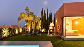 A modern outdoor pool area with a well-maintained lawn, lounge chairs, and a clear sky.
