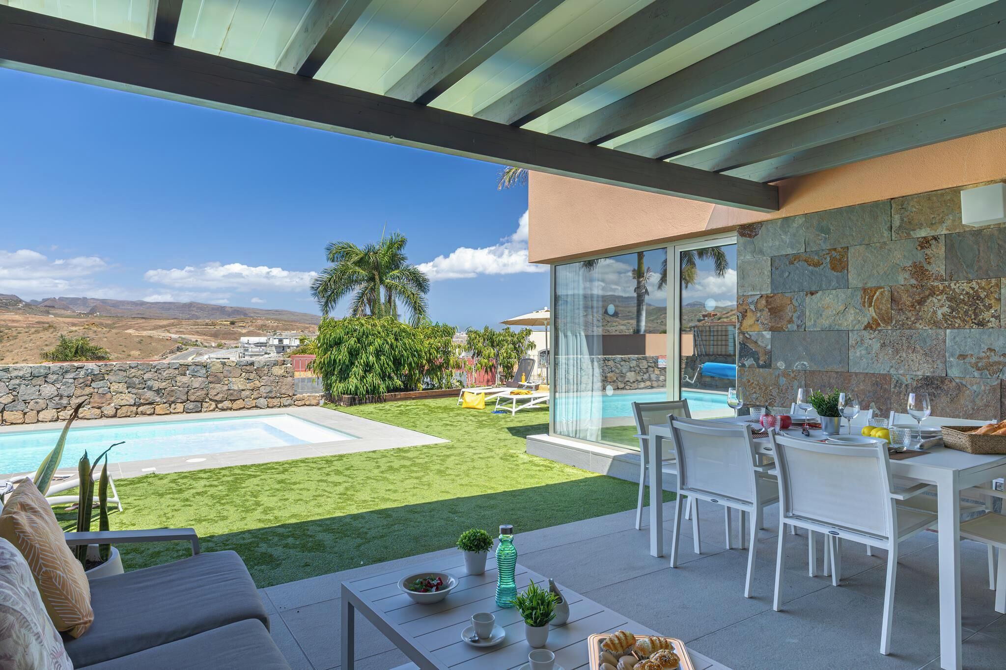 A patio with a pool, outdoor seating, and a view of the landscape.