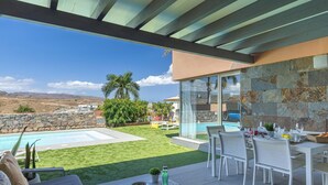A patio with a pool, outdoor seating, and a view of the landscape.