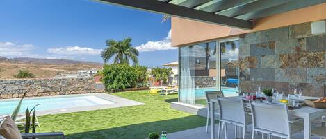A patio with a pool, outdoor seating, and a view of the landscape.