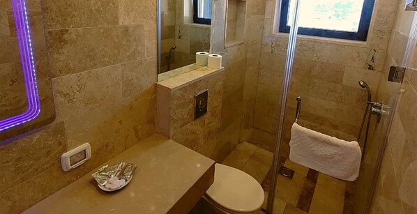 A bathroom with a shower, toilet, and a vanity with a towel rack.