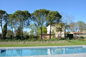 A swimming pool with a stone border, surrounded by a well-maintained lawn and trees. - Villa with private pool, 7bedrooms, in Tuscan country between Cortona and Arezzo (Arezzo)