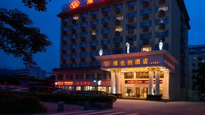 A hotel with a prominent sign in red characters, multiple floors with balconies, and a well-lit entrance. - Vienna Hotel -Yantian Harbor (Shenzhen)