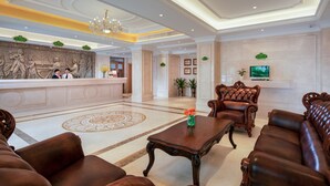 A lobby with a reception desk, a chandelier, a television, and leather seating. - Vienna Hotel -Yantian Harbor (Shenzhen)