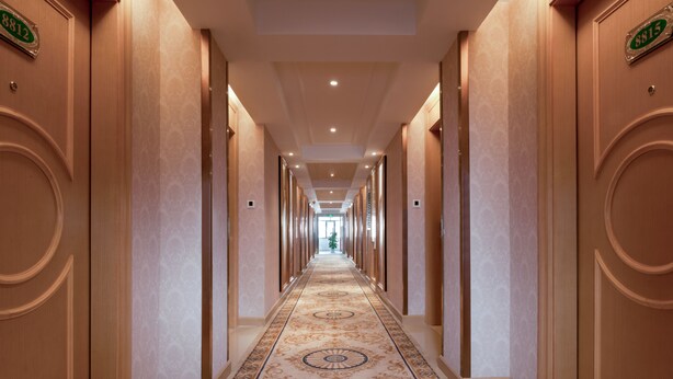 A long, narrow hallway with ornate carpet and wooden doors, each marked with a number. - Vienna Hotel -Yantian Harbor (Shenzhen)