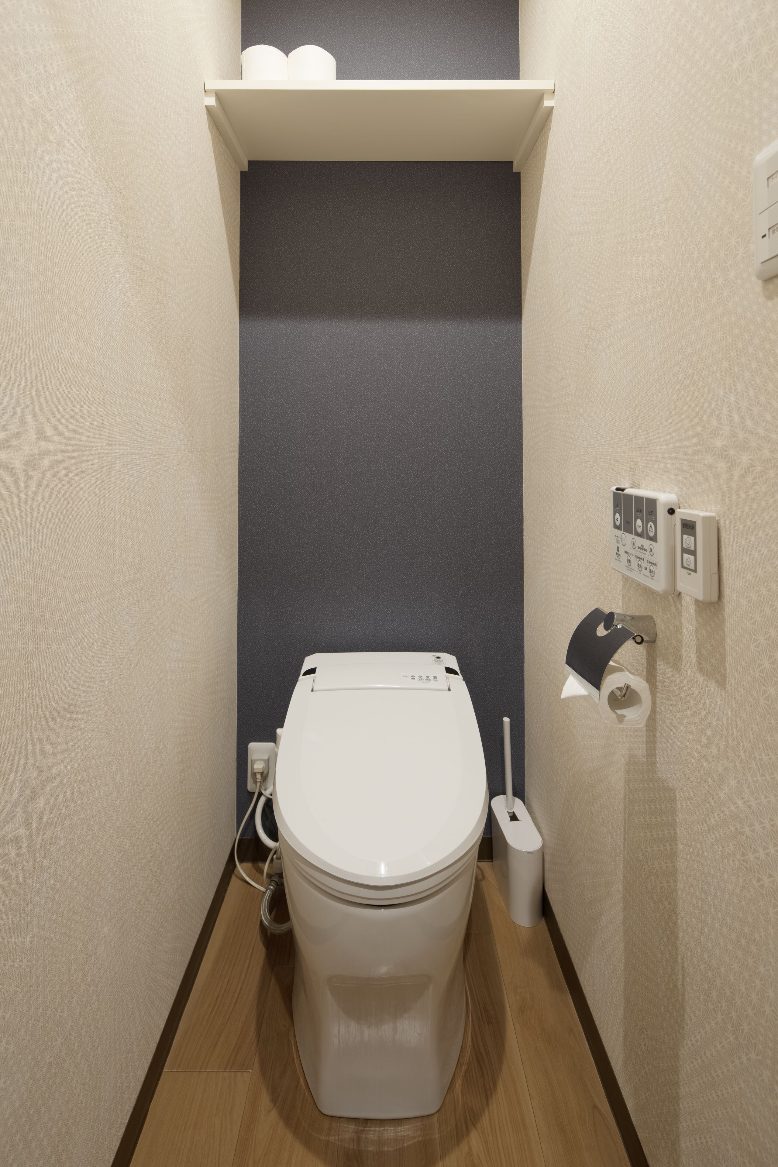 A compact bathroom with a toilet, a paper towel dispenser, and a toilet paper holder on the wall.