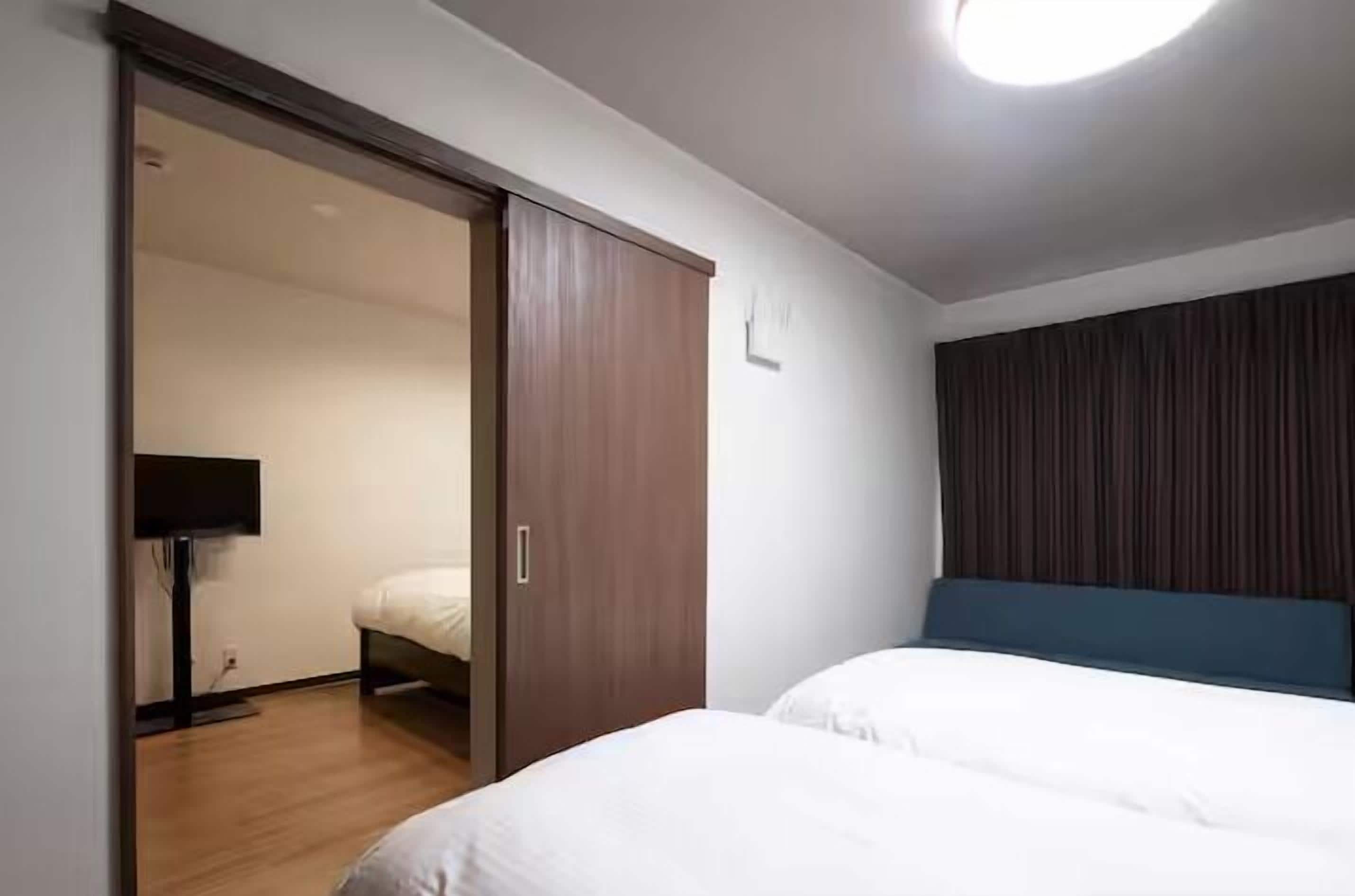 Quarto de hotel com cama, guarda-roupa e televisão.