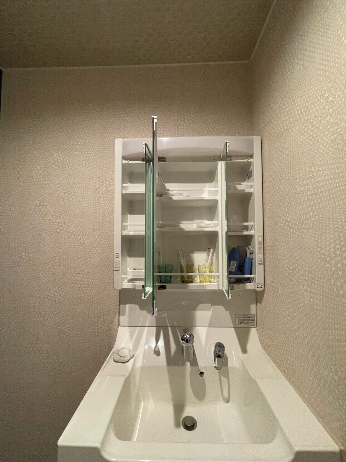 Ein Badezimmer mit einem weißen Waschbecken, einem Spiegelkorpus und einem Handtuchhalter.