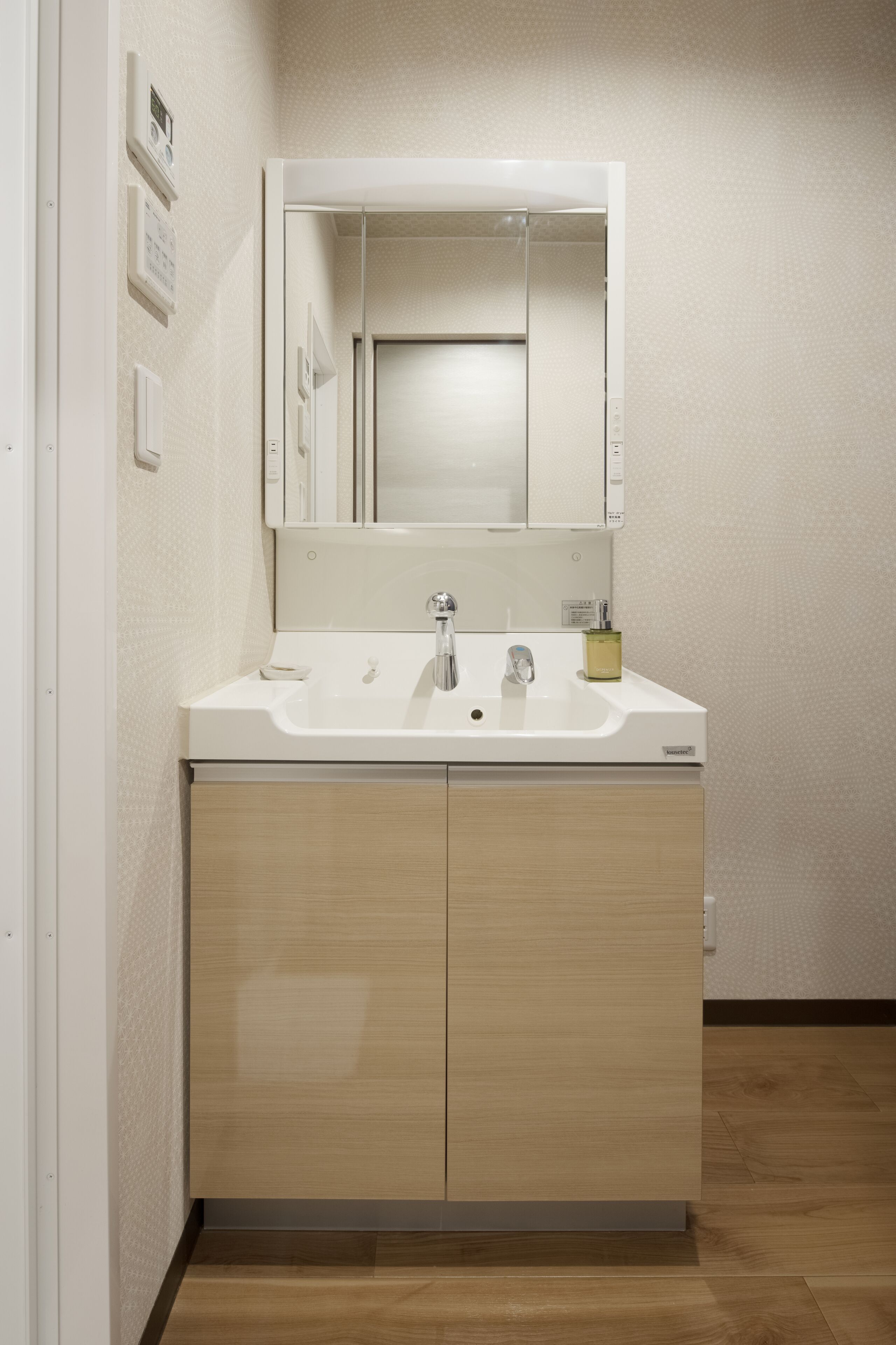 Une salle de bain moderne avec un lavabo blanc, deux robinets, un miroir et un meuble en bois.