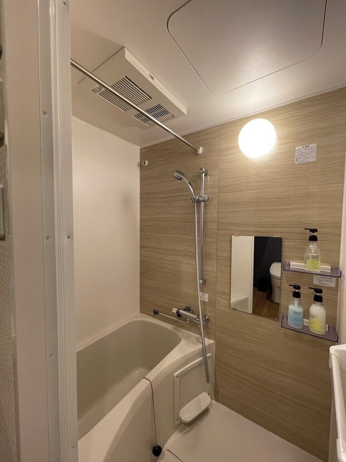Een badkamer met een bad, douche en spiegel.