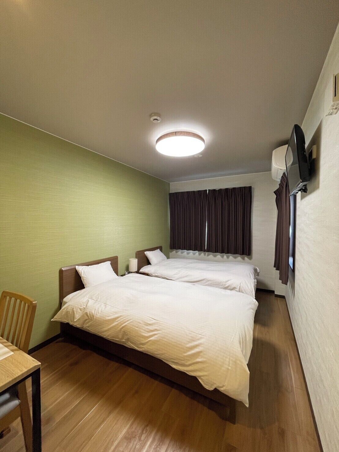 A hotel room with a large bed, a desk, and a chair.