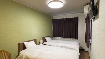 A hotel room with a large bed, a desk, and a chair.