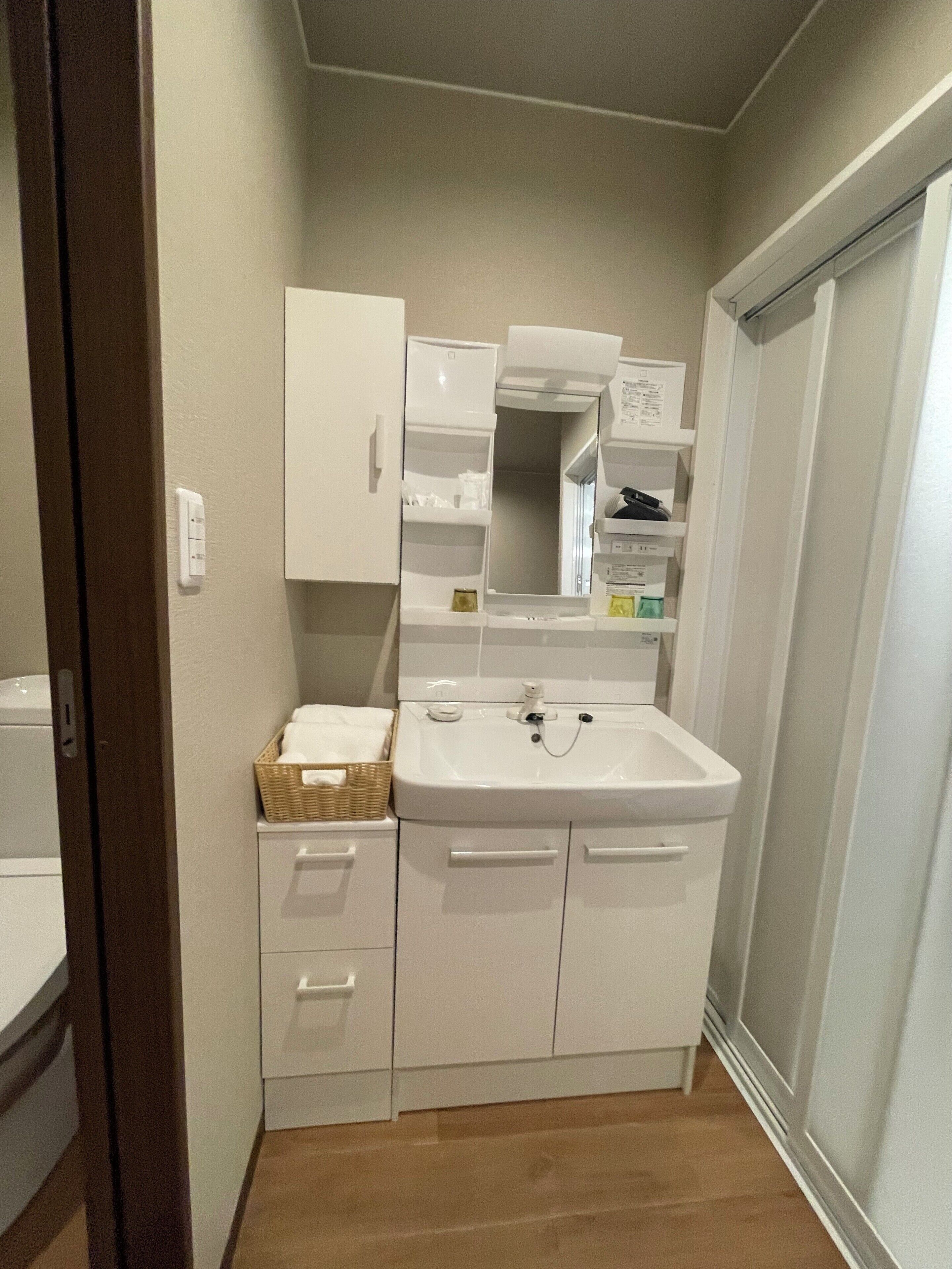 A compact bathroom with a white sink, mirror, and storage cabinets.
