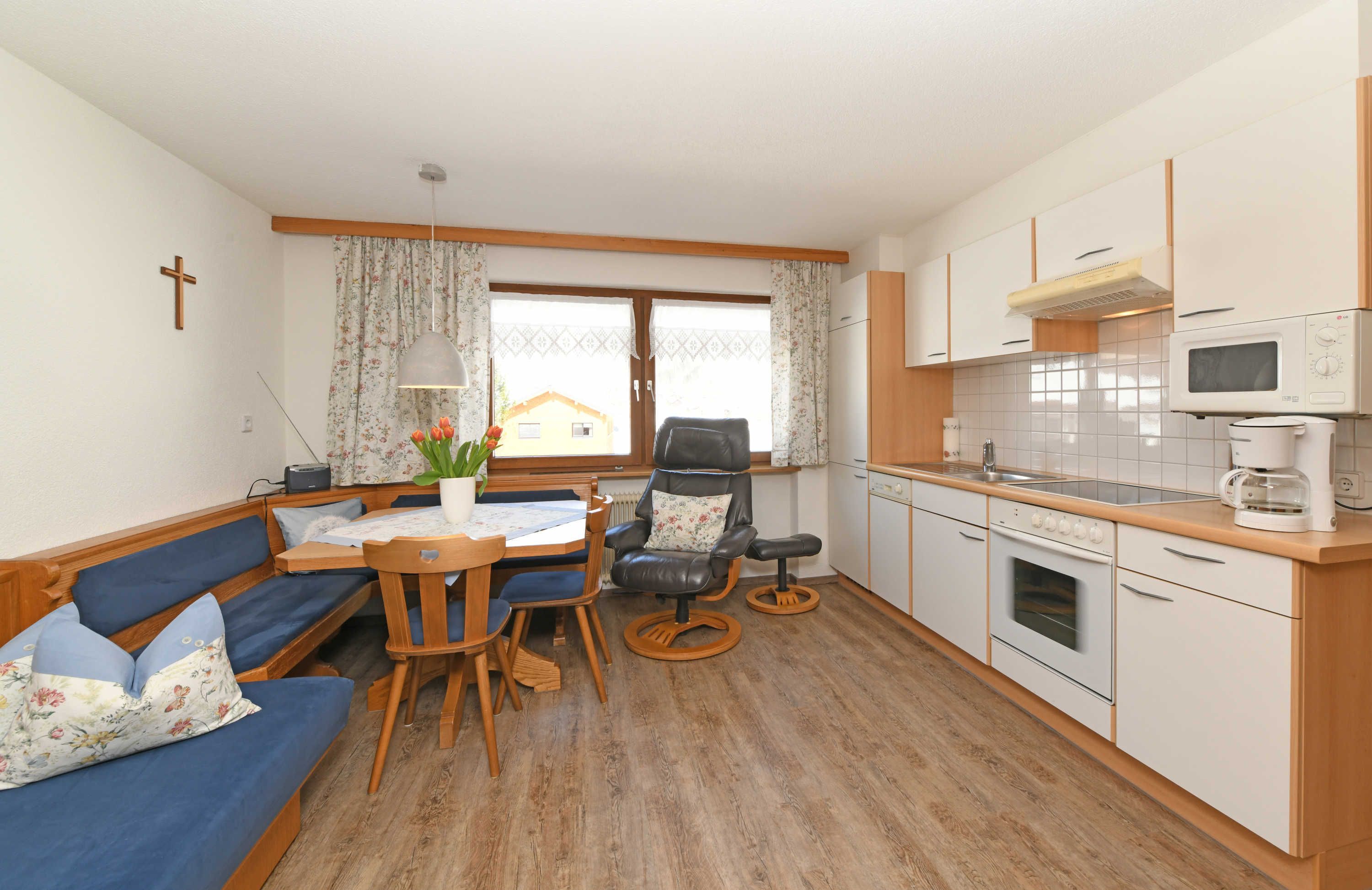 A compact living space with a dining area, a sofa, a chair, a table, a kitchen with a microwave, oven, and cabinets.