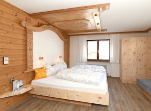 Un dormitorio de madera con cama, ventana y armario.