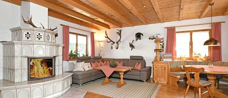 Una sala de estar con chimenea, techo de madera y un comedor con mesa y sillas.