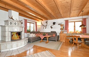 A living room with a fireplace, wooden ceiling, and a dining area with a table and chairs.