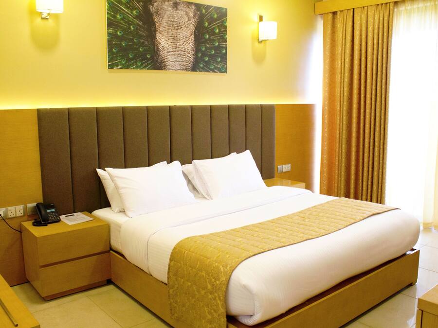 Habitación de hotel con cama, mesitas de noche, teléfono y una lámpara fijada a la pared.
