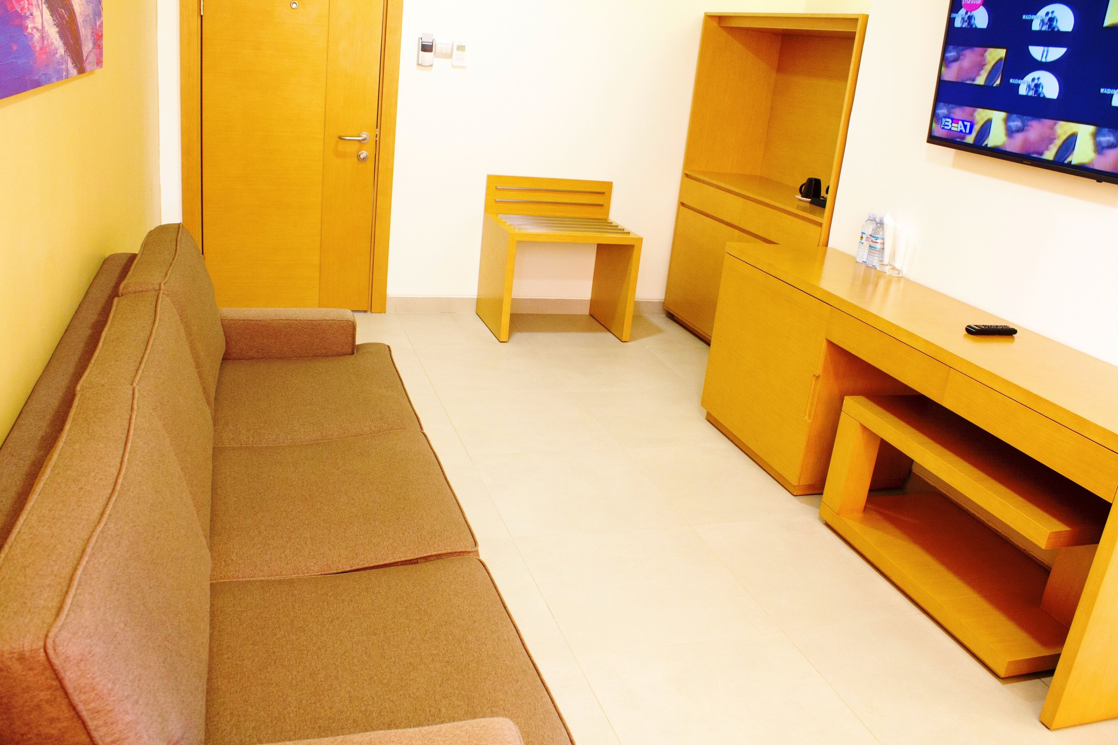 A room with a sofa, a wooden chair, a desk, and a television.