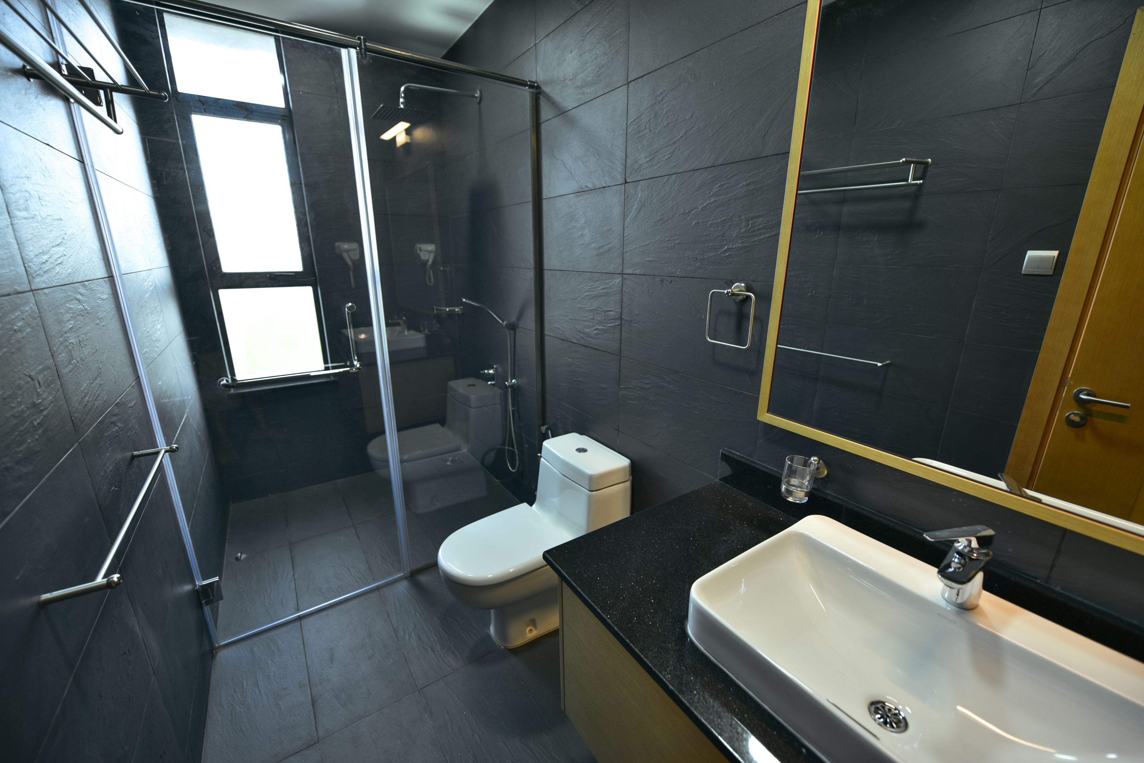 A modern bathroom with a glass-enclosed shower, a white toilet, and a sink with a mirror above it.
