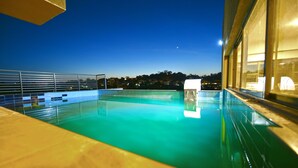 A swimming pool with a clear view of the surrounding buildings and a night sky. - K Hotels (Entebbe)