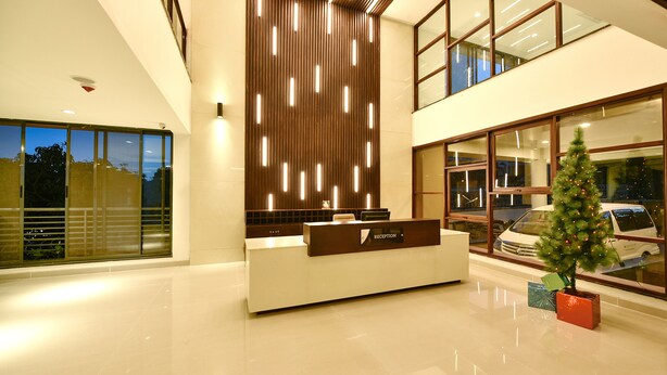 A modern hotel reception area with a reception desk, a Christmas tree, and a large window overlooking the street. - K Hotels (Entebbe)