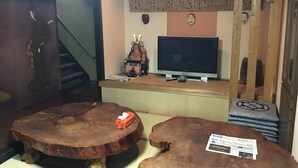 Ein Zimmer mit einem Holztisch, einem Fernseher und einer Treppe.